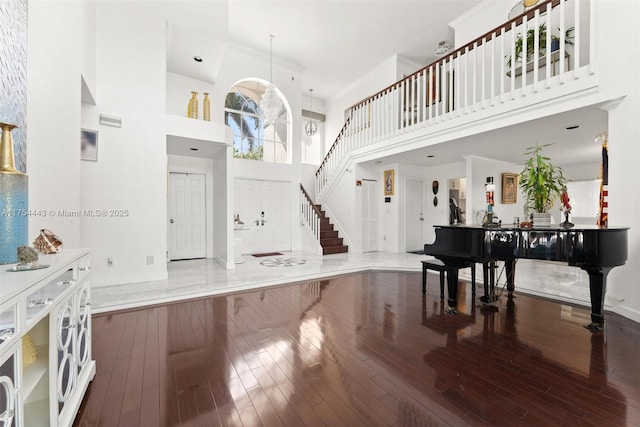 foyer featuring stairs, hardwood / wood-style flooring, a high ceiling, and ornamental molding