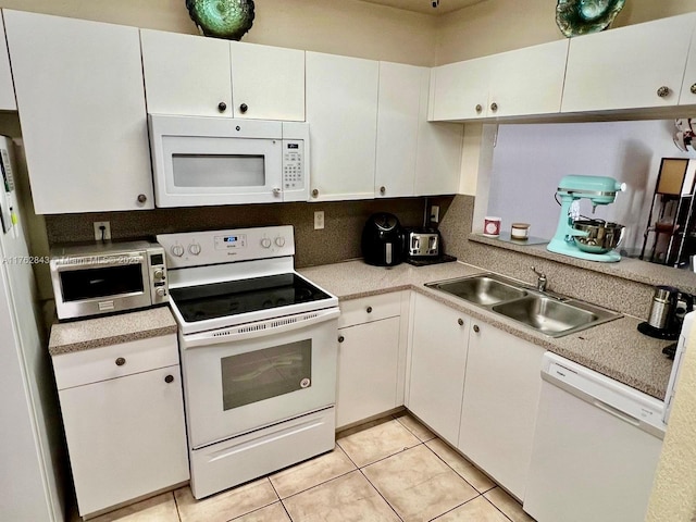 kitchen with light tile patterned floors, white cabinets, white appliances, and a sink