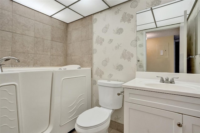 full bathroom featuring a washtub, toilet, vanity, and wallpapered walls