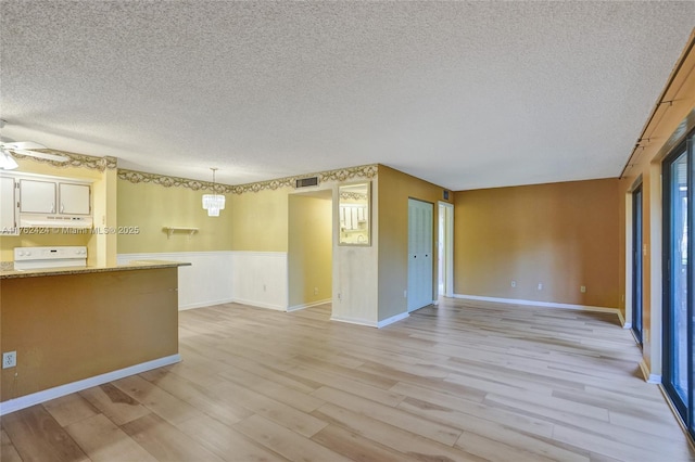 empty room featuring visible vents, a ceiling fan, a textured ceiling, light wood finished floors, and baseboards