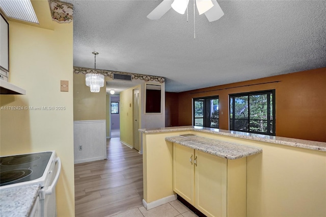 kitchen featuring a textured ceiling, visible vents, pendant lighting, white electric range, and light wood-type flooring