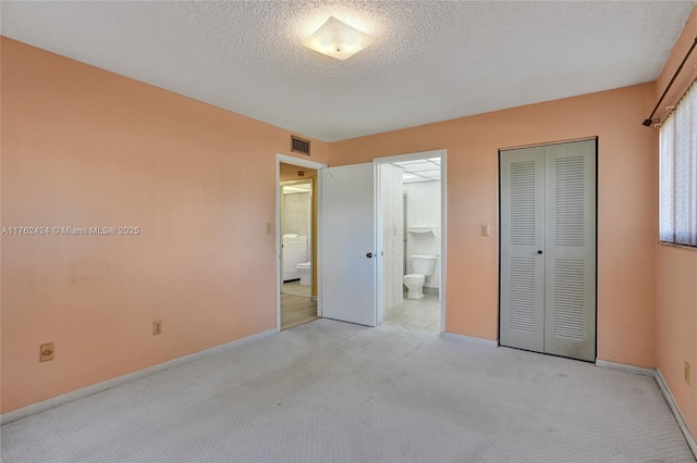 unfurnished bedroom featuring visible vents, a textured ceiling, a closet, connected bathroom, and light colored carpet