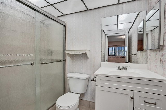 bathroom with vanity, toilet, a shower stall, and wallpapered walls