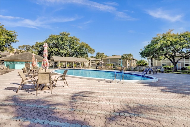 pool with a patio area and fence