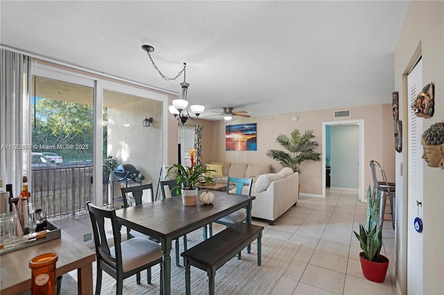 dining space with visible vents, ceiling fan with notable chandelier, floor to ceiling windows, light tile patterned floors, and baseboards