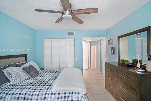 bedroom with light tile patterned floors, visible vents, a textured ceiling, and a closet