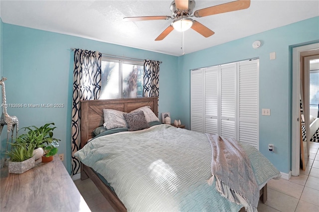 bedroom with light tile patterned floors, a ceiling fan, a closet, and baseboards