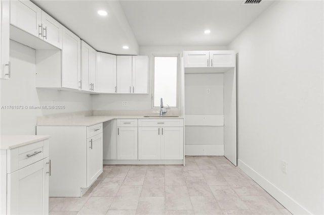 kitchen with a sink, white cabinets, and recessed lighting