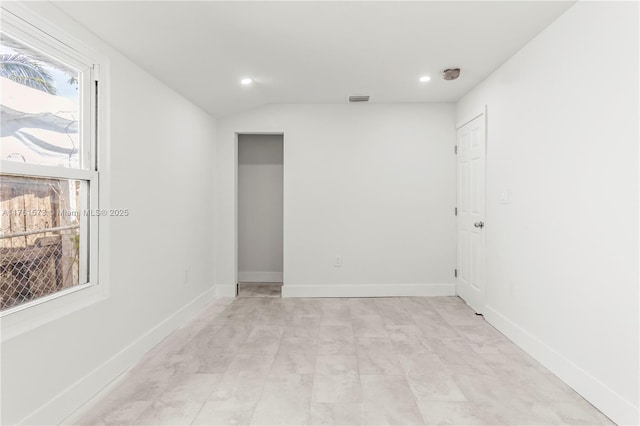 spare room with baseboards, lofted ceiling, visible vents, and recessed lighting