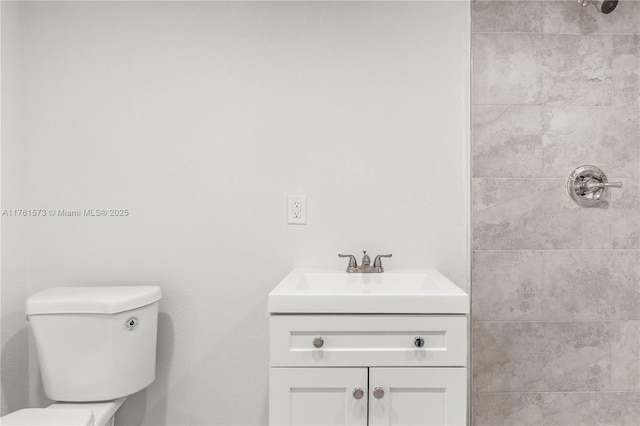 bathroom with vanity, a tile shower, and toilet