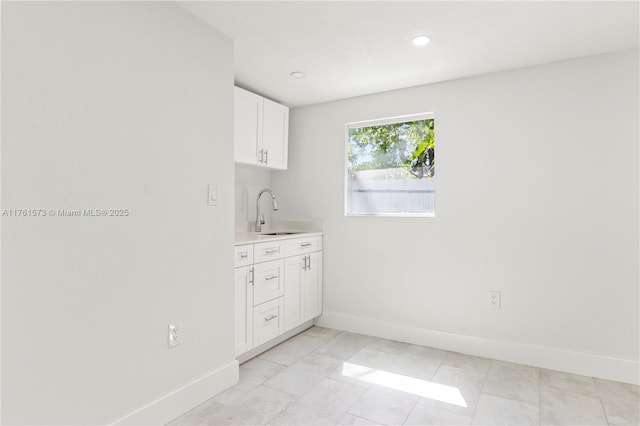 laundry area with a sink, baseboards, recessed lighting, and wet bar