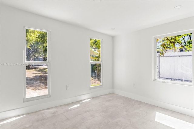 spare room with baseboards and a healthy amount of sunlight