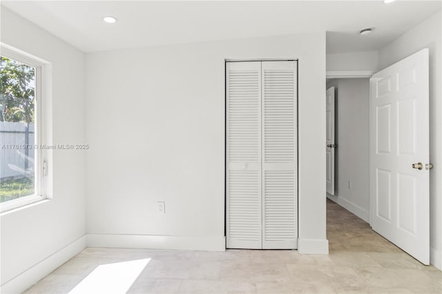 unfurnished bedroom with a closet, baseboards, and recessed lighting