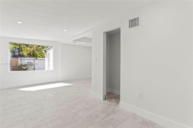 empty room featuring visible vents, baseboards, and recessed lighting