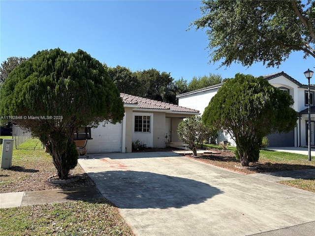 view of front of home with stucco siding, driveway, fence, an attached garage, and a tiled roof