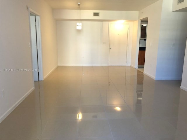 empty room featuring visible vents, baseboards, and tile patterned flooring