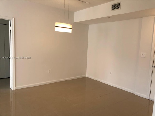 empty room featuring baseboards and visible vents