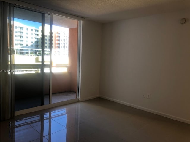 empty room featuring tile patterned flooring, baseboards, and a textured ceiling