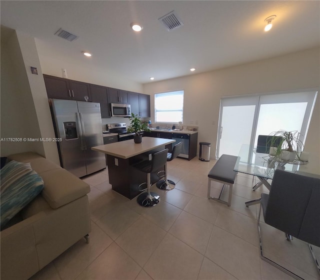 kitchen with stainless steel appliances, visible vents, a center island, and light countertops