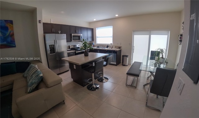 kitchen featuring a center island, light countertops, light tile patterned floors, a kitchen breakfast bar, and stainless steel appliances