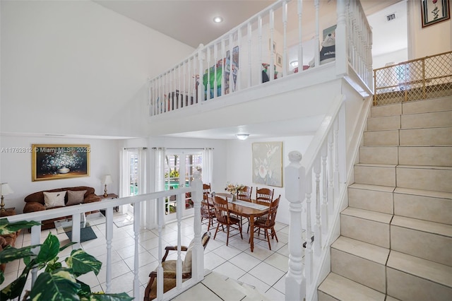 staircase featuring tile patterned floors, visible vents, a high ceiling, and recessed lighting