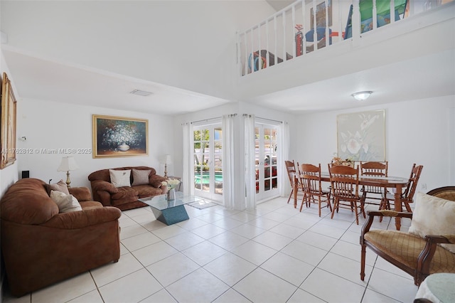 living area featuring visible vents, a high ceiling, and light tile patterned flooring