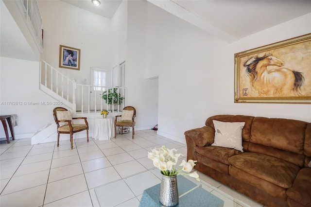 living area featuring light tile patterned floors, stairway, baseboards, and high vaulted ceiling