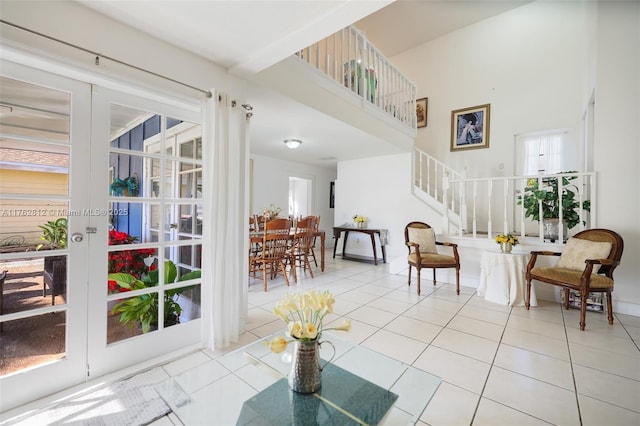 sitting room featuring stairs, tile patterned floors, french doors, and a towering ceiling