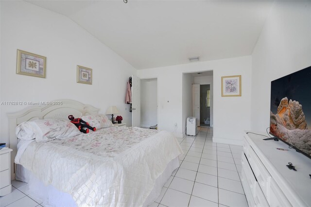 bedroom with lofted ceiling, light tile patterned floors, and visible vents