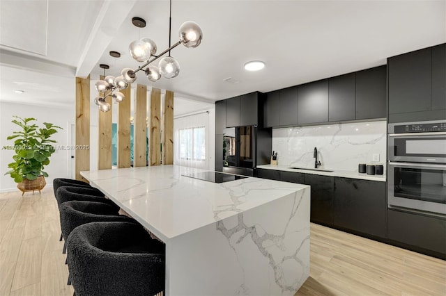 kitchen featuring light wood-style flooring, black appliances, dark cabinetry, and a sink