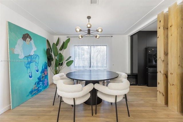 dining area with visible vents, light wood-style flooring, and an inviting chandelier