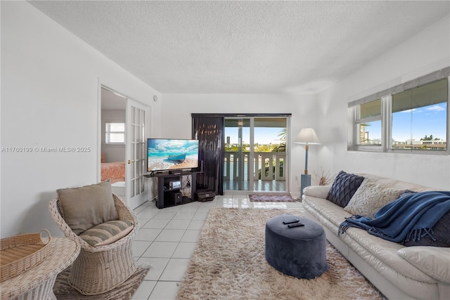 living room featuring light tile patterned floors, french doors, and a textured ceiling