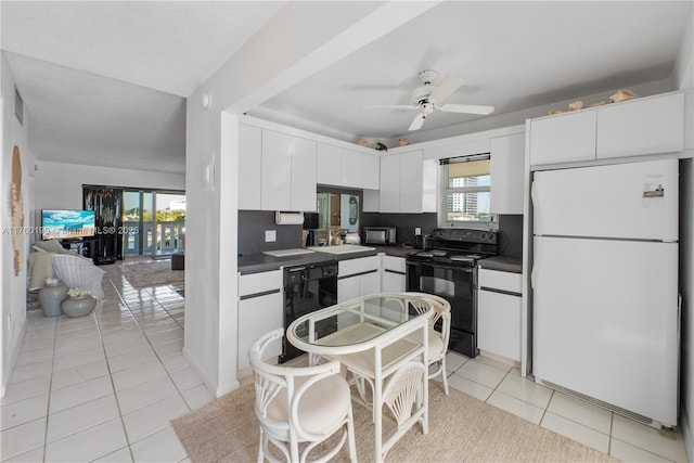 kitchen featuring dark countertops, black appliances, light tile patterned floors, white cabinetry, and a sink