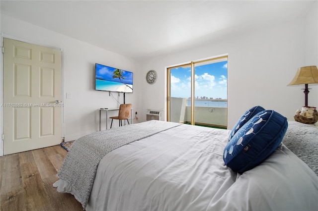 bedroom with access to exterior, a wall mounted AC, and wood finished floors