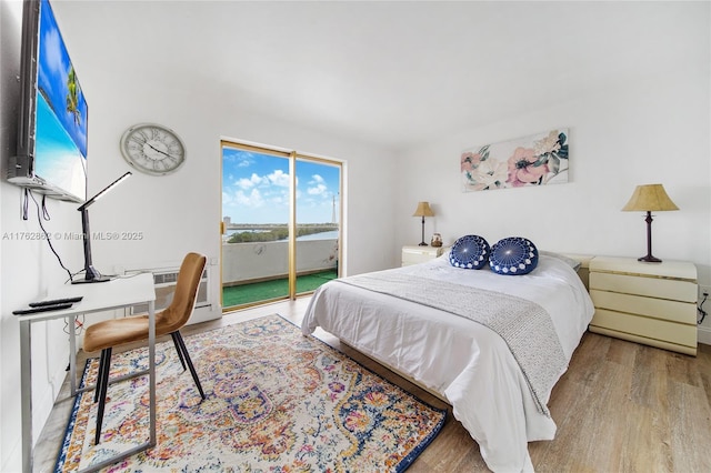 bedroom featuring wood finished floors, an AC wall unit, and access to exterior