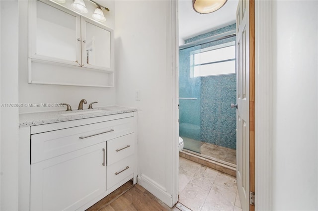 bathroom featuring vanity, toilet, baseboards, and a stall shower