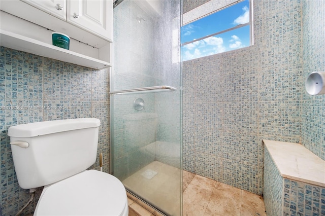 full bath featuring tile patterned floors, toilet, tile walls, and a shower stall