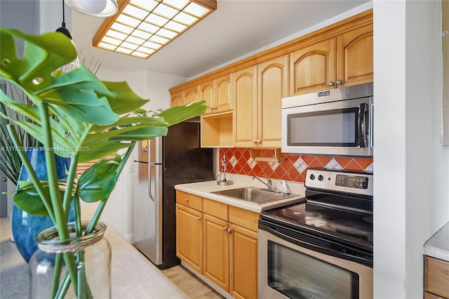 kitchen featuring light brown cabinets, a sink, stainless steel appliances, light countertops, and tasteful backsplash