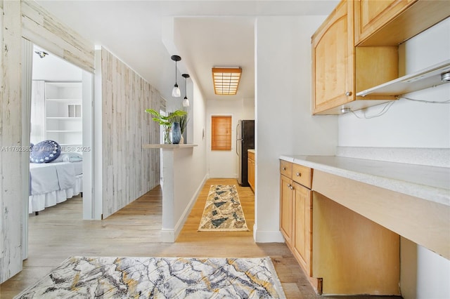 kitchen featuring light wood-style flooring, light brown cabinets, light countertops, and freestanding refrigerator