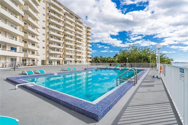 community pool with a patio and fence