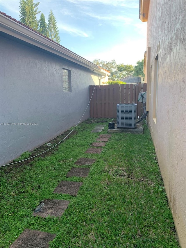 view of yard featuring central AC unit and fence