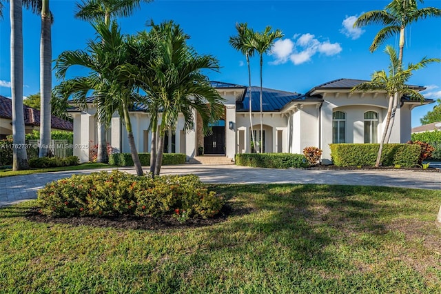 mediterranean / spanish house featuring a front yard, metal roof, driveway, and stucco siding