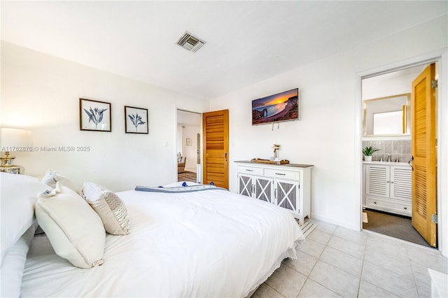 bedroom featuring ensuite bath, light tile patterned floors, baseboards, and visible vents