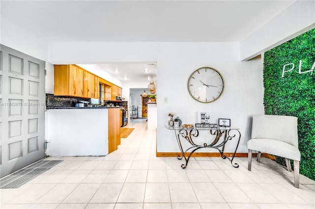 kitchen with dark countertops, light tile patterned floors, baseboards, and decorative backsplash