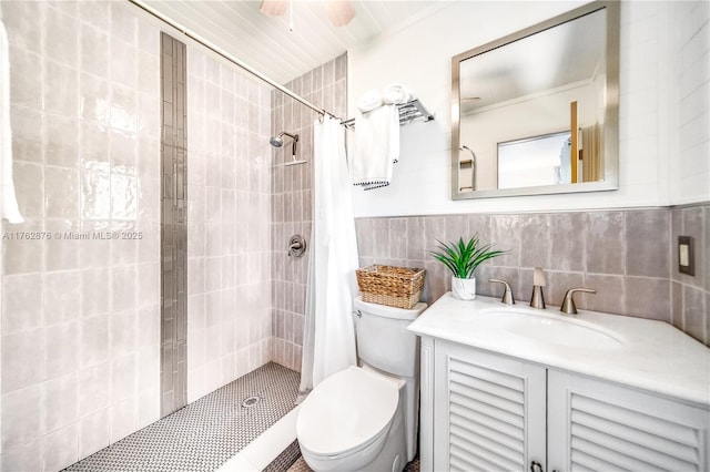 bathroom with tiled shower, vanity, toilet, and tile walls