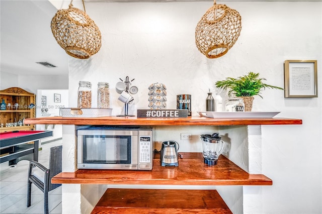 bar featuring stainless steel microwave, visible vents, and tile patterned floors