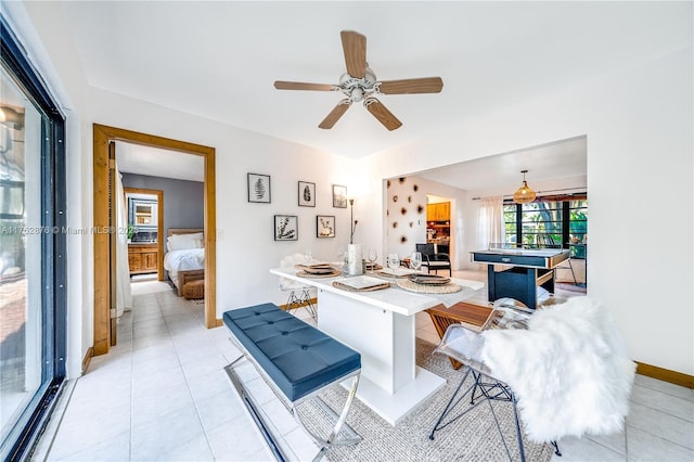 interior space with ceiling fan, baseboards, and light tile patterned flooring