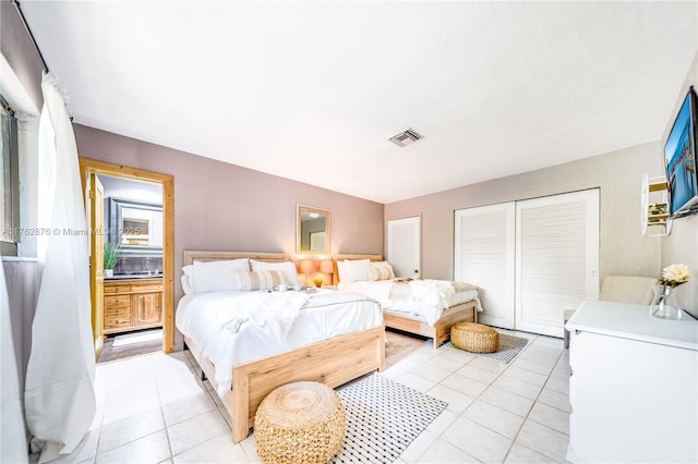 bedroom featuring light tile patterned floors, visible vents, and a closet