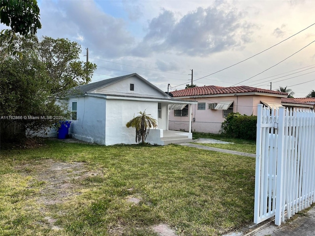 rear view of house with a tiled roof, a yard, fence, and stucco siding