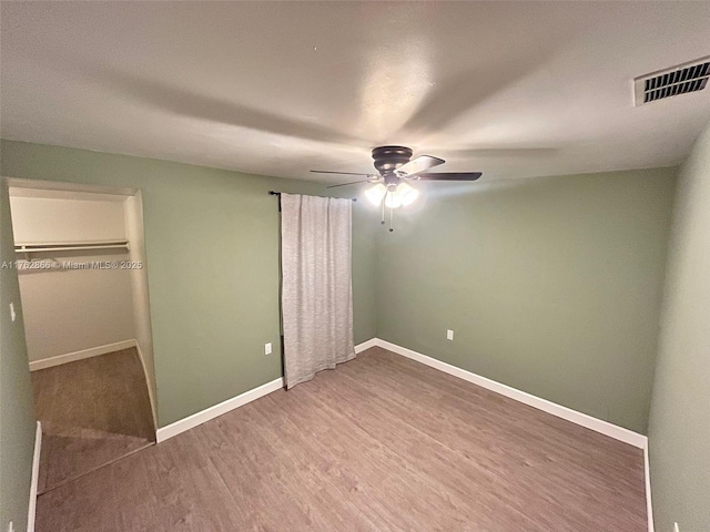 unfurnished bedroom featuring visible vents, baseboards, wood finished floors, and a ceiling fan